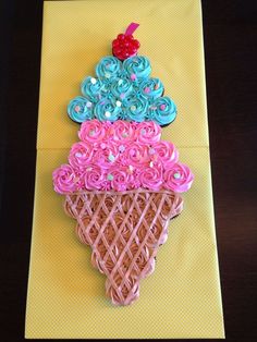 an ice cream cone decorated with pink, blue and green icing on a yellow napkin