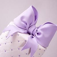 a purple and white hat with a large bow on the top, sitting on a polka dot table cloth