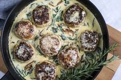 a pan filled with meatballs covered in gravy and topped with fresh herbs