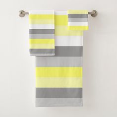 two yellow and gray striped towels hanging on a towel rack next to a white wall