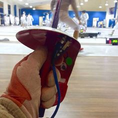 a person is holding something in their hand while standing on a skateboard at an indoor skating rink