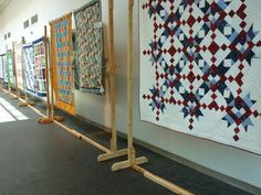 rows of quilts on display in an art gallery