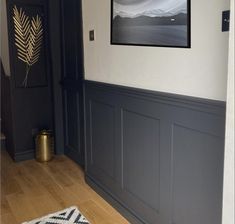 an empty room with wood floors and gray painted paneling on the walls, along with a rug