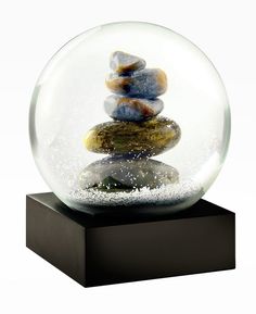 a snow globe filled with rocks on top of a wooden base and black stand against a white background