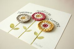 three crocheted flowers sitting on top of a card