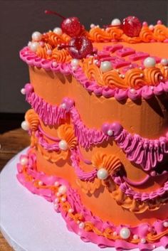 a three tiered cake decorated with pink and orange icing