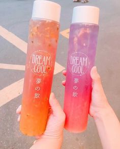 two people holding up plastic bottles with liquid in them that say dream cool and dream cool