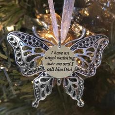 a christmas ornament with a butterfly on it's side and the words, i have an angel watching over me and i call him dad