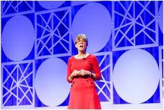 a woman in a red dress is standing on stage with her hands together and looking at the camera