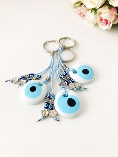 the evil eye keychain is blue and has silver beads on it, with flowers in the background