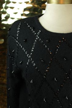 "Adding a some sparkle to a cold day, the black embellished Karen Scott Petites sweater highlights:  ✶Adorable long sleeve crew neck pullover with drop shoulder silhouette  ✶Quirky, black sequinned argyle design along bodice front and sleeves  ✶Dangling teardrop beaded tassles throughout  ✶Ribbed hemming along sleeve cuffs & bottom hem  ✶Shoulder pads included  ✶58% Silk 30% Nylon 10% Angora 2% Wool   ✩MEASUREMENTS    Size: PS (Would fit best on an X-Small or Small)    Bust: 37\"    Waist: 33\"    Shoulder-Shoulder: 20\"    Sleeve Length: 25\"    Total Length: 23 1/2\" ✶CONDITION: Very Good: used, with very minor flaws, no repairs are necessary.                           Wear. Missing two beads at wearer L shoulder                          (She's clean and ready to karaoke to Don't Speak b Embellished Sweater Outfit, Preppy 80s, Lace Fabric Diy, Diamond Sweaters, Upcycle Clothing, Beaded Stuff, Knit Wear, Bead Embroidery Tutorial, Embellished Sweaters