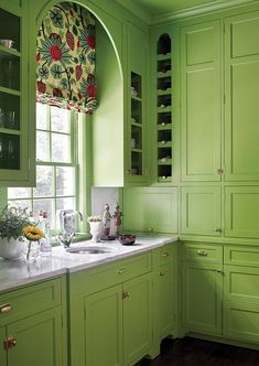 a kitchen with green cabinets and white counter tops