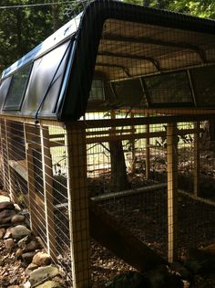 a small caged in area with trees and rocks on the ground next to it