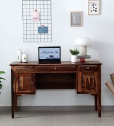 a laptop computer sitting on top of a wooden desk next to a potted plant