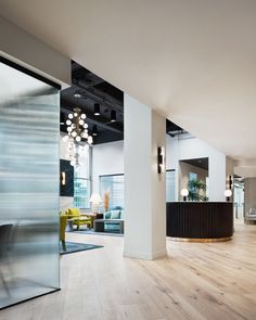 an office lobby with wood flooring and modern lighting hanging from the ceiling, along with glass partitions