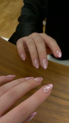 a woman with pink nail polish on her nails and two hands holding something in front of her