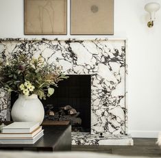 a white vase filled with flowers sitting on top of a table next to a fireplace