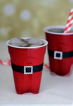 two red cups decorated with santa claus's belt and candy canes on a table