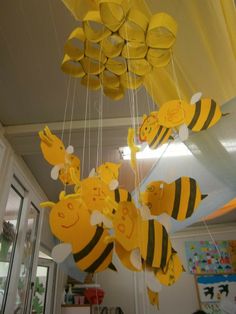 some yellow and black paper honeybees hanging from the ceiling in an office building