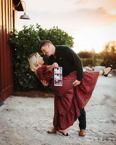 a man and woman are dancing together in the sand near a red building at sunset