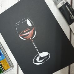 a drawing of a glass of wine on a table next to some paintbrushes