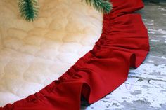 a heart shaped pillow with ruffled edges on a wooden floor next to a christmas tree