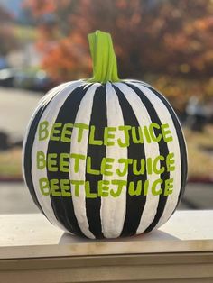 a black and white striped pumpkin with the words beetlejuice written in green on it