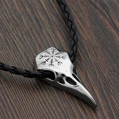 a black and white necklace with a silver skull on it's side, sitting on a wooden surface