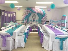 a room filled with lots of tables covered in purple and white table cloths next to balloons