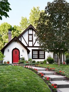 a house with steps leading up to it and flowers in the front yard, along with landscaping