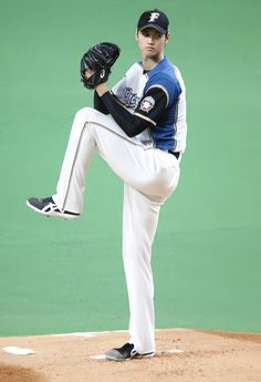 a baseball player pitching a ball on top of a pitchers mound with his leg in the air