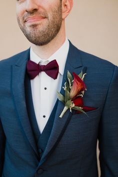 a man in a blue suit with a red rose boutonniere on his lapel