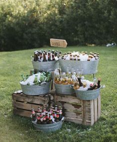 several buckets filled with beer sitting on top of a grass covered field next to trees