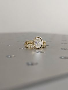 two gold rings with diamonds on top of each one, sitting on a silver surface