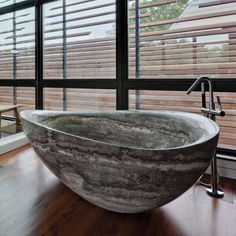 a large stone bathtub sitting on top of a wooden floor next to a window