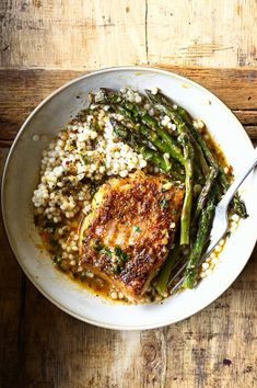 a white plate topped with meat and asparagus