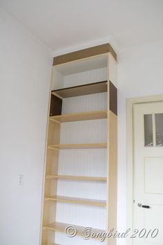 an empty room with white walls and wooden shelves