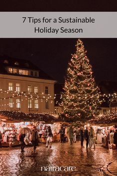 a large christmas tree is lit up in the middle of a city square at night