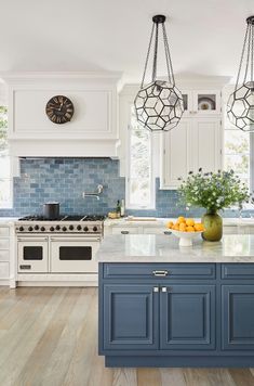 a kitchen with blue cabinets and an island in front of the stove top is surrounded by hanging chandeliers