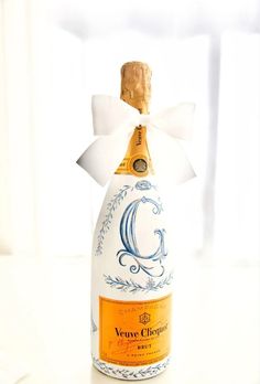 a bottle of wine with a white bow on it's top and the letter g