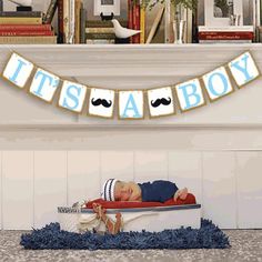 a baby is sleeping on a bed with his name banner in the shape of a mustache