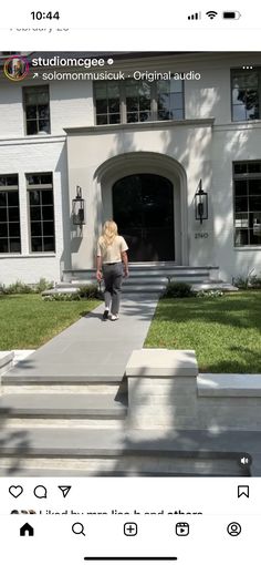 a person walking down the sidewalk in front of a house