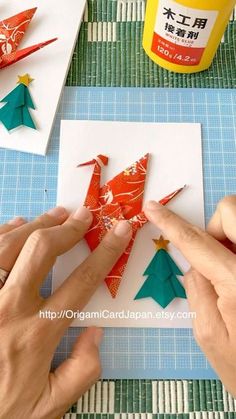 someone making origami christmas trees out of paper