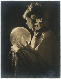 an old black and white photo of a woman holding a crystal ball