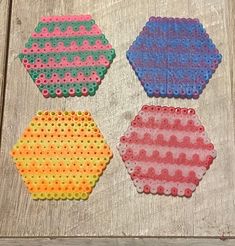 four different colored hexagons are on a wooden surface with holes in them