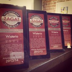 three award plaques sitting on top of a counter next to a brick wall in a restaurant