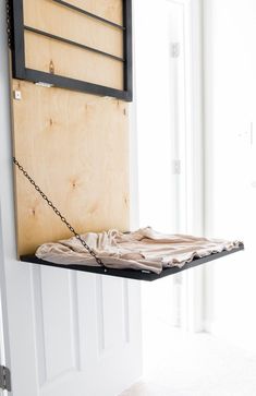 a wooden wall hanging on the side of a door with a chain attached to it