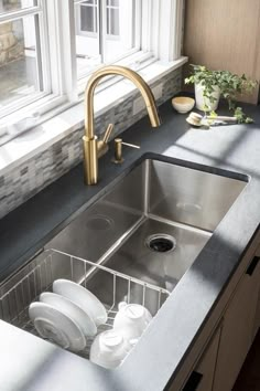 a stainless steel kitchen sink in front of a window