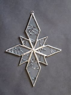 a silver snowflake ornament on a gray surface