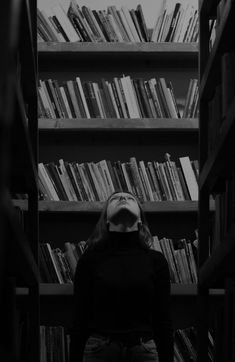 a person standing in front of a bookshelf with many shelves full of books